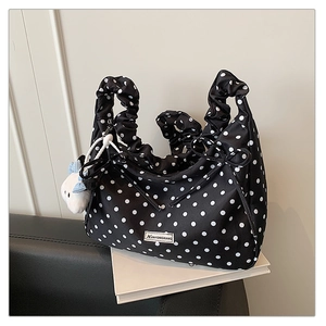 Detail of black polka dot pleated bag with ruffled handle and plush charm accessory