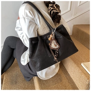 Detail einer großen schwarzen Wildleder-Tote-Bag mit Herzanhänger und Quaste auf der Schulter