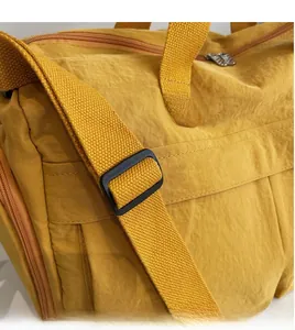 Close-up of the adjustable wide fabric shoulder strap on a yellow nylon travel bag