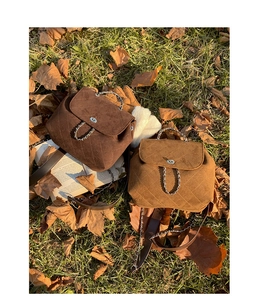 Close-up of quilted suede mini backpacks in dark brown and yellow with chain straps