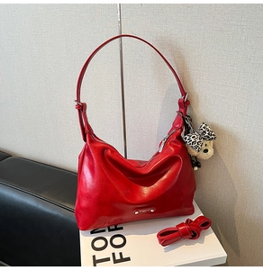 Detail of red glossy leather shoulder bag with metallic logo and cute bear charm