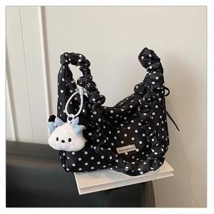 Close-up of black polka dot handbag with ruffled handle and plush charm detail