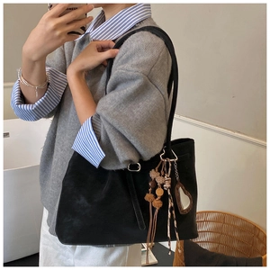 Detail der schwarzen Wildleder-Shopper-Tasche mit Herzanhänger getragen von Modell
