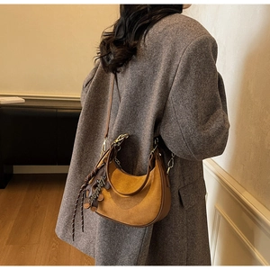 Détail du sac demi-lune en daim marron avec boucles dorées et pendentif London