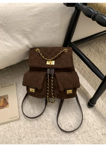 Detail view of retro brown suede quilted backpack with gold twist locks on white rug