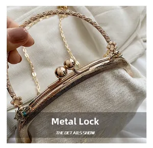 Close-up of golden floral engraved hardware handle and bead clasp on white bag