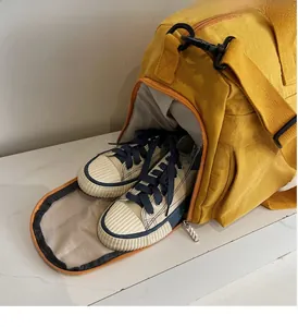 Detail of travel fitness bag featuring a side shoe compartment with canvas sneakers