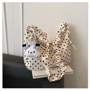 Detail of ruffle shoulder strap and white polka dot pattern on the beige handbag
