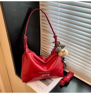 Detail of red faux leather hobo bag with teddy bear charm and adjustable shoulder strap