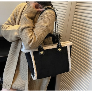 Close-up of black suede tote bag with cream shearling trim and gold chain shoulder strap