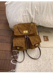 Detailed view of the brown suede quilted backpack with gold turn-lock and chain straps