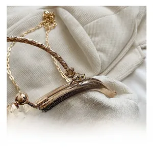 Close-up of golden vintage metal clasp with floral carving and chain on white knit bag