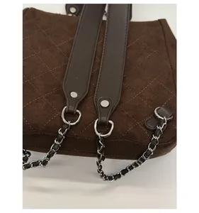 Close-up of quilted dark brown suede backpack with silver chain strap and leather details