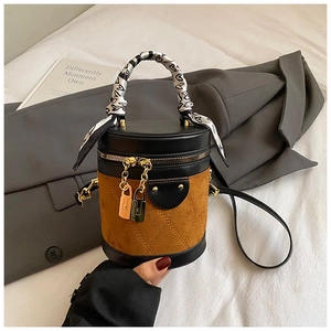 Detail of cylinder bag featuring black leather, brown suede stitching and silk scarf handle