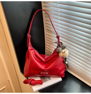 Detailed shot of a red hobo bag featuring a plush bear charm and metallic logo hardware