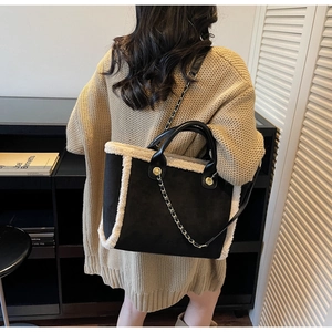 Detail of black suede tote bag with white shearling trim and metal chain strap