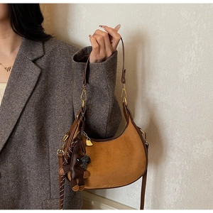 Sac hobo en daim marron avec charm ours et fermetures dorées porté sous le bras au modèle
