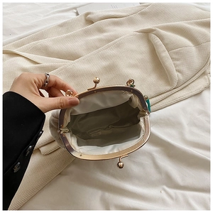 Detail view of open shell bag with gold hardware, satin lining, and green tassel accent