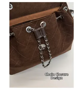 Detail view of the silver chain drawstring closure on a brown suede quilted bag