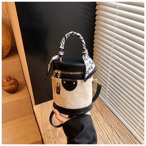 Detail of cylinder bucket bag with beige quilting, silk scarf handle and gold padlock