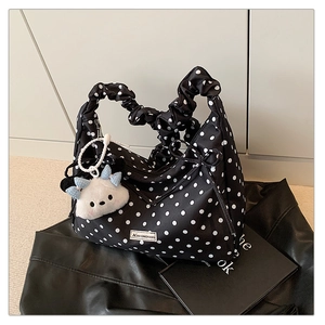 Close-up of black polka dot handbag with ruffled handle and white cloud charm accessory