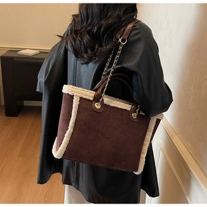Detail of suede tote bag with faux shearling trim and gold metal chain shoulder strap
