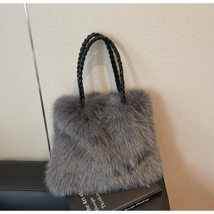 Detail of dark grey faux fur tote bag with black woven handles on art book