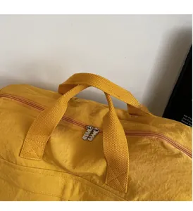 Detail of reinforced yellow nylon handles and dual metal zippers on large travel bag