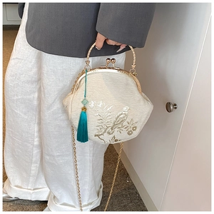 Detail of embroidered fabric handbag with a golden handle and blue silk tassel charm