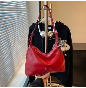 Close-up of red hobo bag texture with a cute teddy bear and leopard bow charm