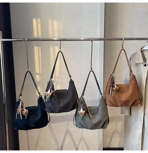 Détail de sacs cabas en cuir mat de diverses couleurs avec charms oursons décoratifs