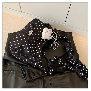 Detail of polka dot tote bag with plush cartoon pendant and metal logo on leather