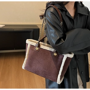Detail of dark brown suede tote bag with cream shearling trim and chain link strap