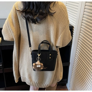 Black vintage shoulder bag with plush pendant shown from behind on a female model