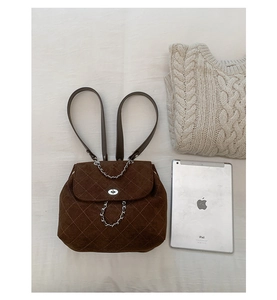 Detailed view of brown quilted suede backpack with chain strap next to a tablet