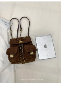 Detail of brown quilted suede backpack with gold twist lock and chain strap