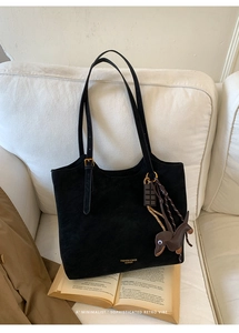 Detail of black tote bag with fashion gold logo and cute dachshund leather pendant