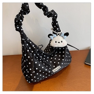 Detailed view of polka dot tote bag with ruffled shoulder strap and plush dog charm