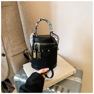 Detail of black cylindrical bucket bag with gold hardware and heart print scarf handle