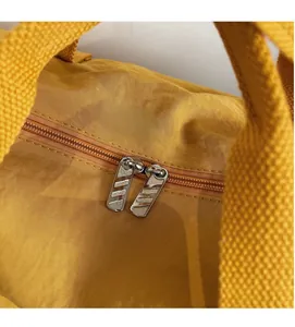 Detailed macro view of the smooth dual-way metal zippers on a yellow travel bag