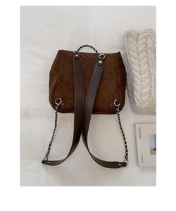 Detailed view of dark brown quilted suede backpack with stylish chain strap on a white cloth