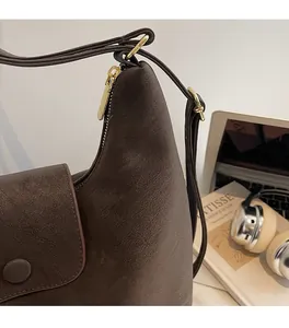 Détail d'un sac à bandoulière marron foncé à texture mate et fermeture éclair dorée