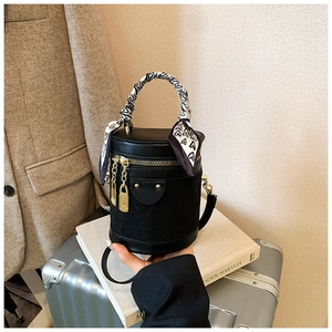 Detail of black cylindrical bucket bag with quilted leather and heart scarf