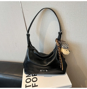 Detail of black faux leather crescent bag with silver zip and leopard heart keychain
