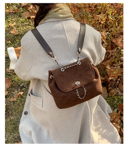 Brown quilted suede backpack with metal chain straps worn by model in autumn outdoor setting