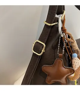 Détail d'un sac à main en daim marron foncé avec breloque étoile et boucles dorées
