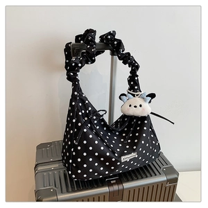 Close-up of black polka dot tote bag with pleated straps and a cute plush charm