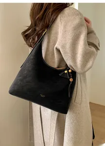 Detail of black suede hobo bag with contrast stitching and golden hardware on model