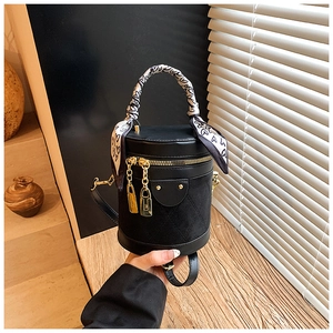 Detail of black cylindrical bucket bag with heart scarf handle and gold zippers