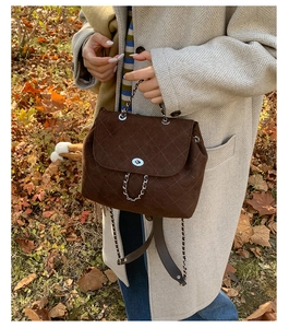 Close-up of brown quilted suede backpack with silver chain handle and twist lock detail